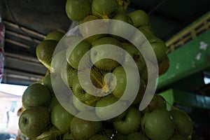 Close up of pile of fresh local green apples in fruit basket hanging on traditional fruit shop for sale