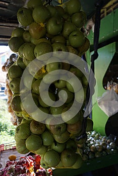 Close up of pile of fresh local green apples in fruit basket hanging on traditional fruit shop for sale