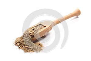 Close-up of pile of ground cardamom spice in a wooden spoon on w