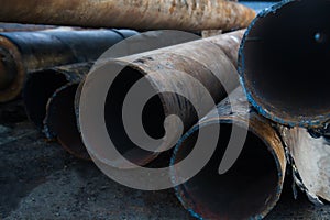 Close up of a pile of large and rusting steel pipes lying