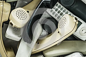 Close up of a pile of old, broken, and dusty laptops in a pile for recycling. They are dirty, and many are missing