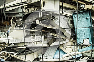 Close up of a pile of old, broken, and dusty laptops in a pile for recycling. They are dirty, and many are missing