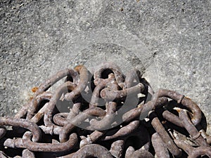 Close up of a pile of old rusty chain on rock