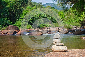 Close up pile of pebbles with beautiful landscape view of small waterfall in the river with water stream flowing through stone.