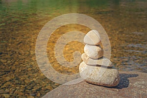 Close up pile of pebbles with clear water of river in the background.