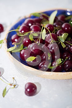 Close up of pile of ripe cherries in blue bowl.
