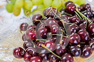 Close up of pile of ripe cherries with stalks and leaves. Large collection of fresh red cherries. Ripe cherries