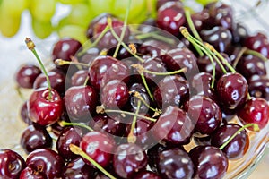 Close up of pile of ripe cherries with stalks and leaves. Large collection of fresh red cherries. Ripe cherries