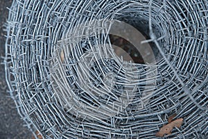 Close up on a pile roll of shiny new barbed wire for fence fencing. Security protection law enforcement. Prison jail