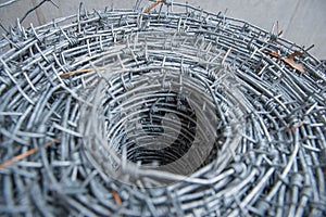 Close up on a pile roll of shiny new barbed wire for fence fencing. Security protection law enforcement. Prison jail