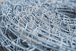 Close up on a pile roll of shiny new barbed wire for fence fencing. Security protection law enforcement. Prison jail