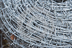 Close up on a pile roll of shiny new barbed wire for fence fencing. Security protection law enforcement. Prison jail