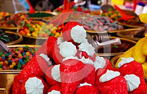 Close up of pile of sweets in shape of strawberry with blurred bowels filled with sweet candies on French market