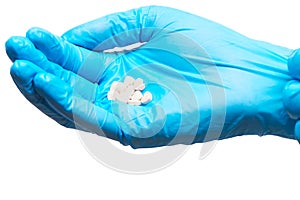 Close up of pile of white heart shape tablets on female doctor's hand in blue sterilized surgical glove