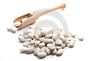 Close-up of pile of white kidney beans in a wooden spoon on whit