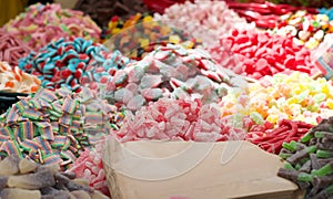 Close up of piles of colorful jelly candies in a market. Paper bags for buy and pack the sweets. Assorted of junk food