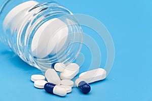 Close up of Pills spilling out of pill bottle on blue background. with copy space. Medicine concept.