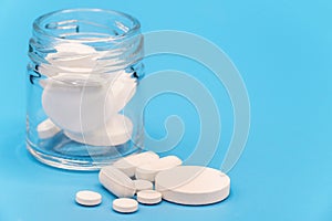 Close up of Pills spilling out of pill bottle on blue background. with copy space. Medicine concept.