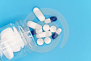 Close up of Pills spilling out of pill bottle on blue background. with copy space. Medicine concept. Top view.