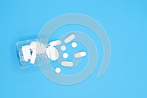 Close up of Pills spilling out of pill bottle on blue background. with copy space. Medicine concept. Top view.