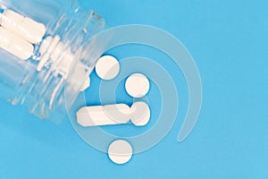 Close up of Pills spilling out of pill bottle on blue background. with copy space. Medicine concept. Top view.