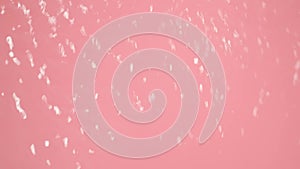 In the close up on a pink background is a flow of water that is directed somewhere, blurring the image. Demonstration of