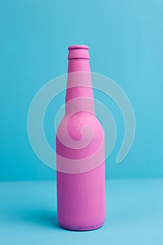 Close up of pink beer bottle on blue background. Deceptive attra