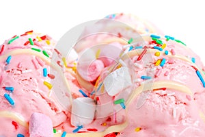 close up of pink berry scoops ice cream strewed sprinkles, marshmallows and icing isolated on white