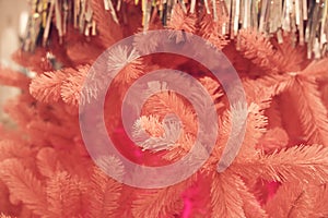 Close up of pink Christmas tree with metallic tinsel glitter rain, background with copy space. Branches with silver