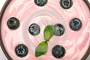 close up pink creamy homemade blueberries fruit yogurt with a fresh green mint leaf texture background