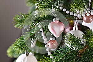 Close up of pink heart ornament on decorated Christmas tree with pink and white tree ornaments like baubles, stars