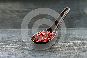 Close up pink peppercorn in spoon dark background
