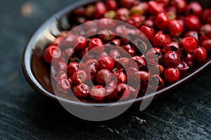 Close up pink peppercorn in spoon dark background