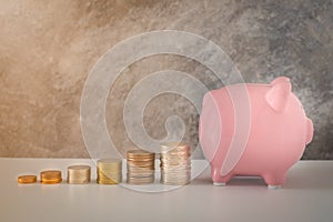 Close-up of pink piggy bank smile with coins stack stair step up growing growth saving money.