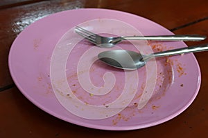 Close-up of pink plastic plates and utensils that have been eaten on the dining table.