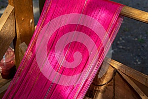 Close up of pink silk weaving on loom