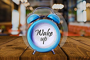 Wake up text on Alarm Clock on wooden table