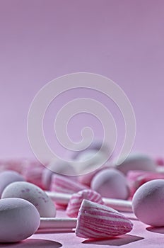 Close up of pink and white candies on pink background with copy space and selective focus