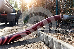 Close-up pipe hose of sewage truck car engine emptying home sewerage tank. Septic cleaning vacuum service and