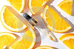 close up of pipette with pouring liquid serum with vitamin C and shadows on white background. Trendy cosmetics shot with hard