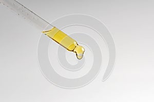 Close up of pipette with pouring liquid serum on white background. Trendy cosmetics shot. Skin care concept