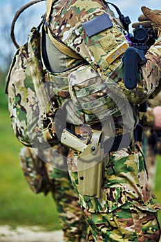 Close-up of a pistol in a holster and a submachine gun in the hands of a soldier