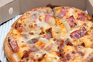 Close up of pizzas with variety of toppings and cheese in cardboard take out boxes with open lid