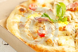 Close up of pizzas with variety of toppings and cheese in cardboard take out boxes with open lid on wooden table