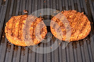 Close up of plant based burger patties on griddle being grilled