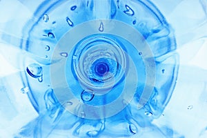 Close-up of a Plastic Bottle Bottom with Leftover Water Drops and Reflections. Global Warming, Water Supply Shortage, Recycling