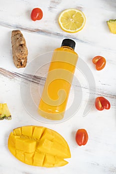 Close up of a plastic bottle of the mixed fruit and vegetable juice by cold pressed with organic ingredients place around on a