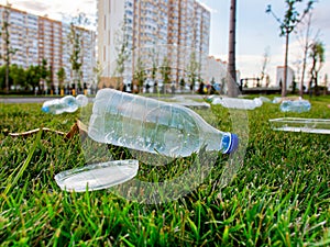 Close-up of plastic bottles and bottle caps on the grass in the park, littering the environment. The problem of global