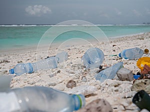 CLOSE UP: Plastic canisters and bottles are scattered around the tropical shore.