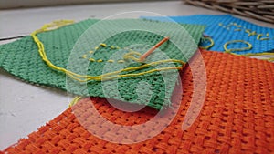 Close up of a plastic needle and thread on a crochet sheet